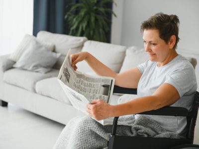woman-wheelchair-reading-newspaper-indoors